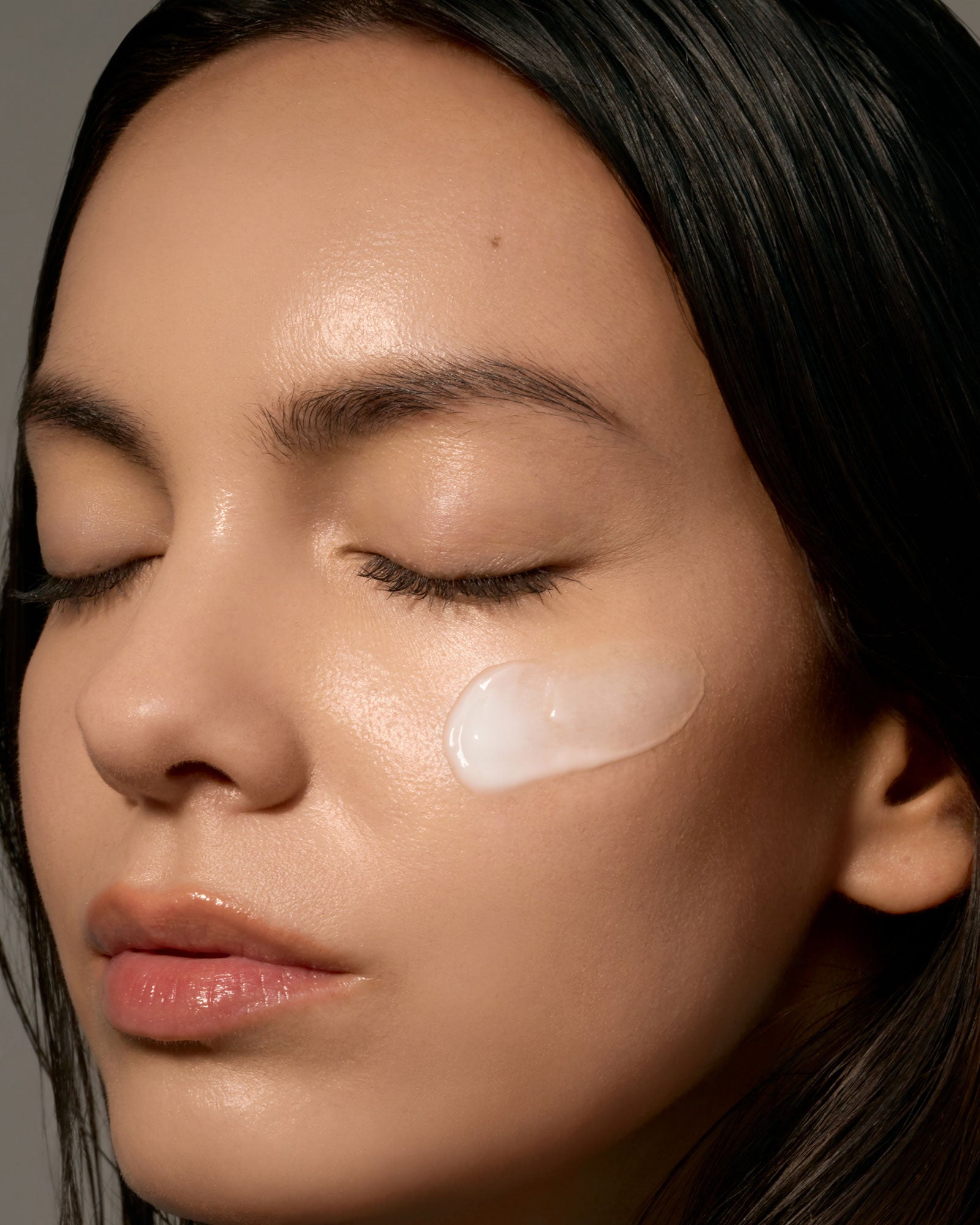 Close-up of a woman's face with a skincare product applied to her cheek.