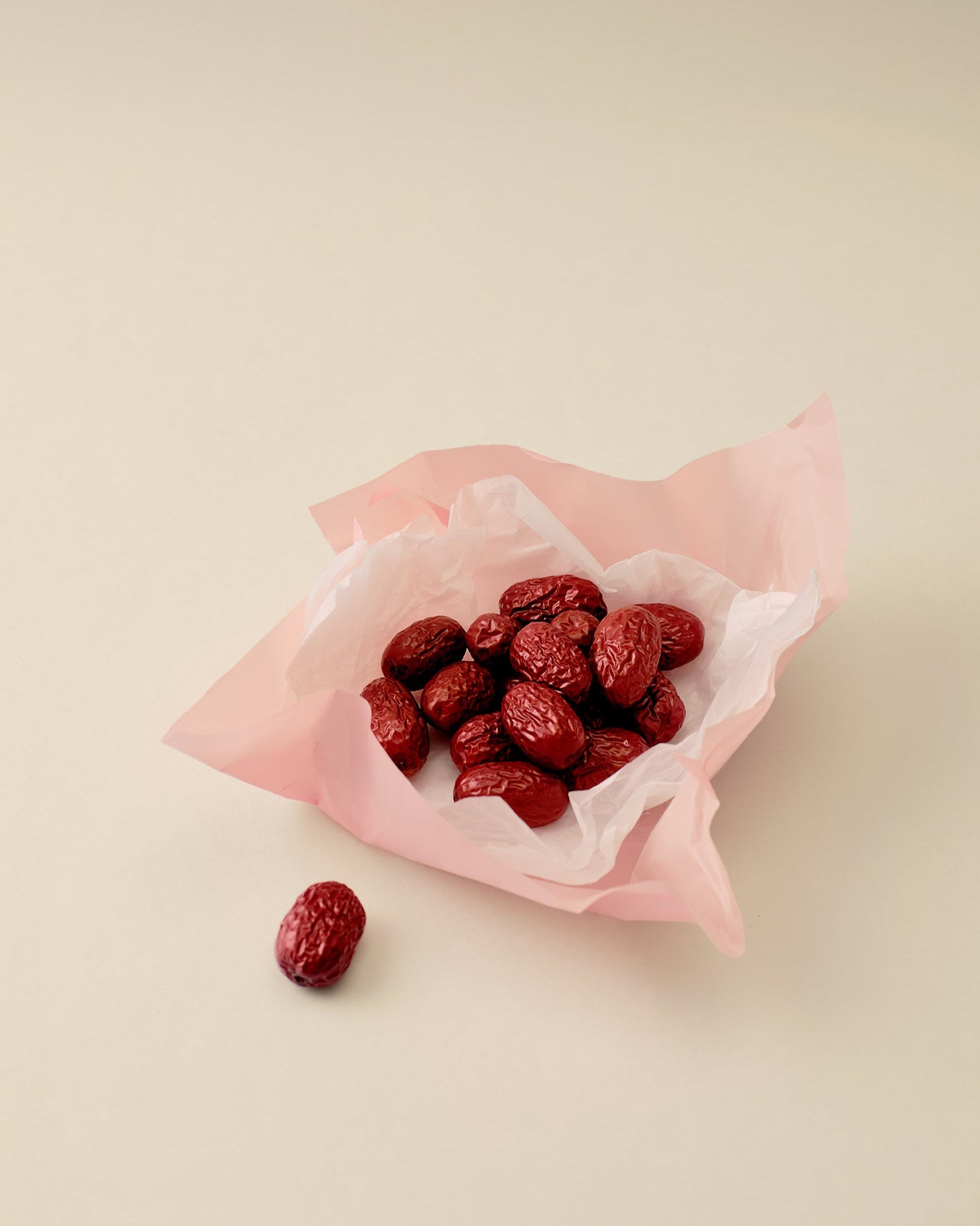 Red dates in a pink paper bag on a beige background