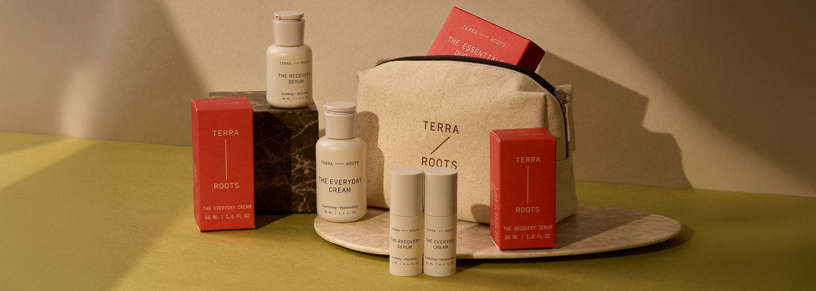 Terra & Roots skincare products including bottles, boxes, and a bag on a green surface.
