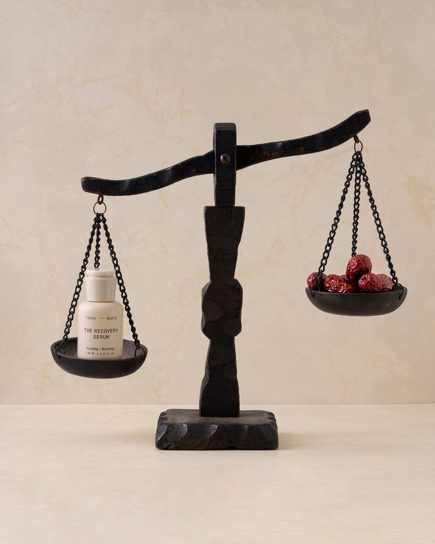 Balance scale with a skincare bottle and jujube on a beige background